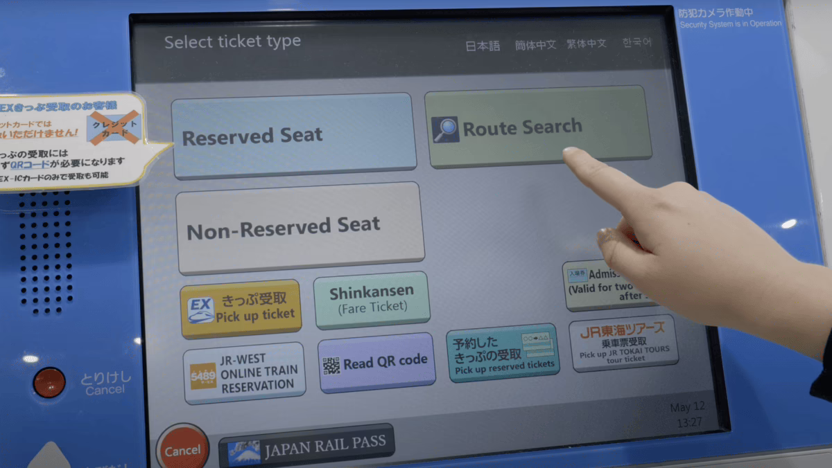 User selecting route search option on a ticket vending machine for Japan Rail Pass, simplifying train travel planning.