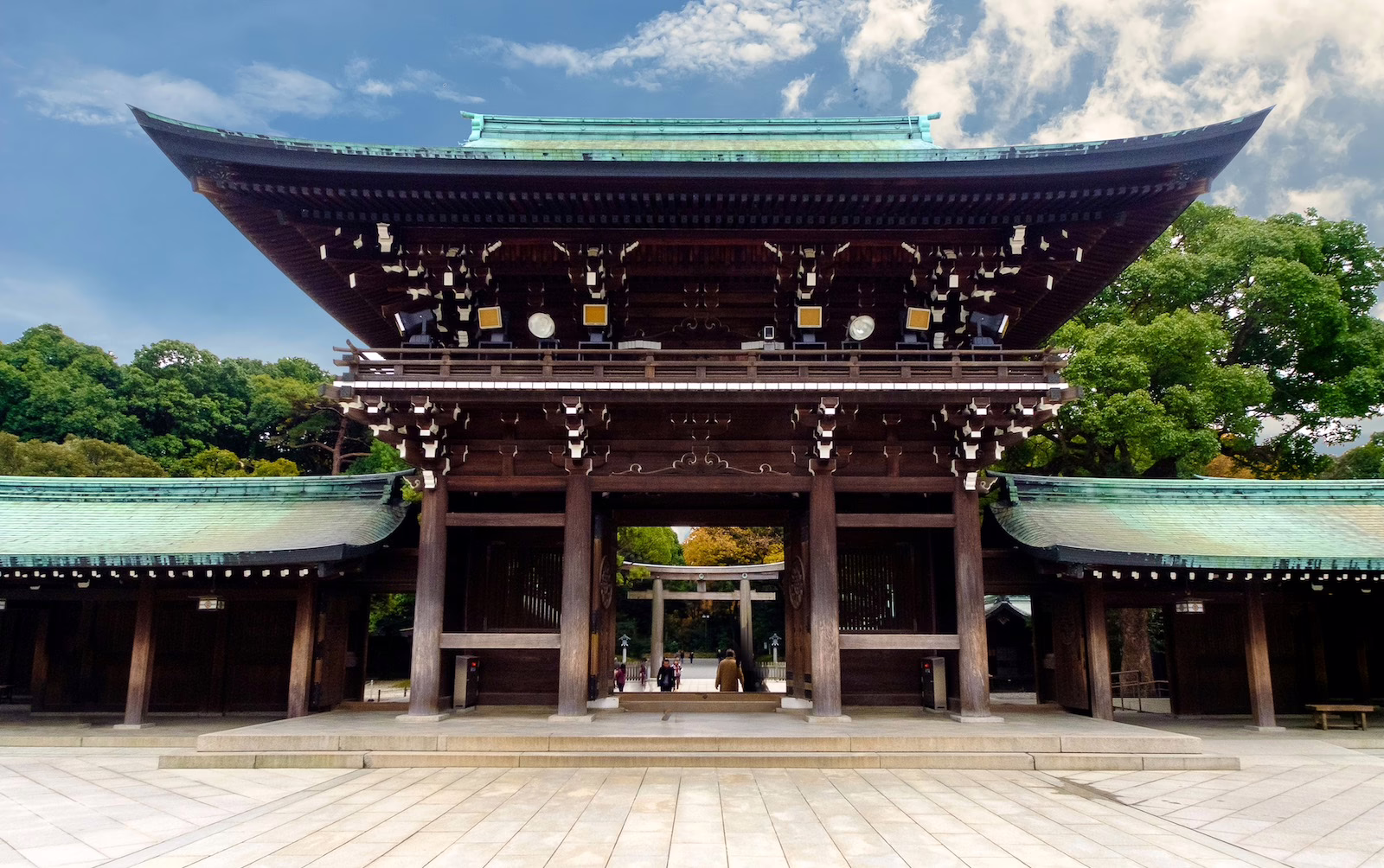 Historic wooden shrine entrance surrounded by lush greenery, symbolizing traditional Japanese architecture and culture.
