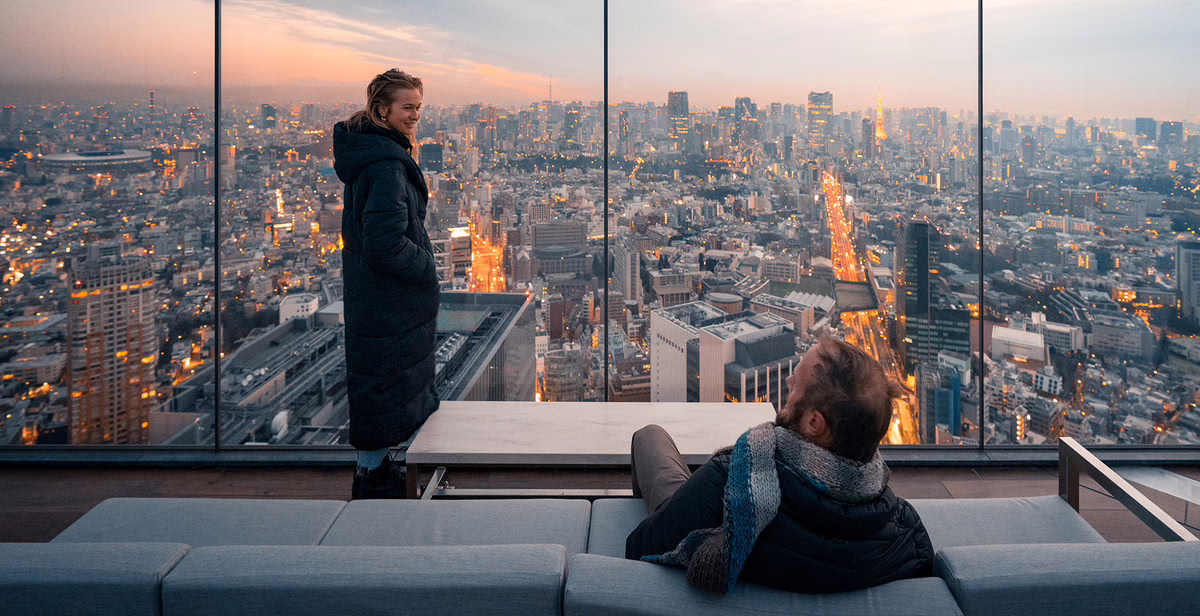Couple enjoying a romantic moment in a high-rise lounge with panoramic city views at sunset, capturing urban romance.