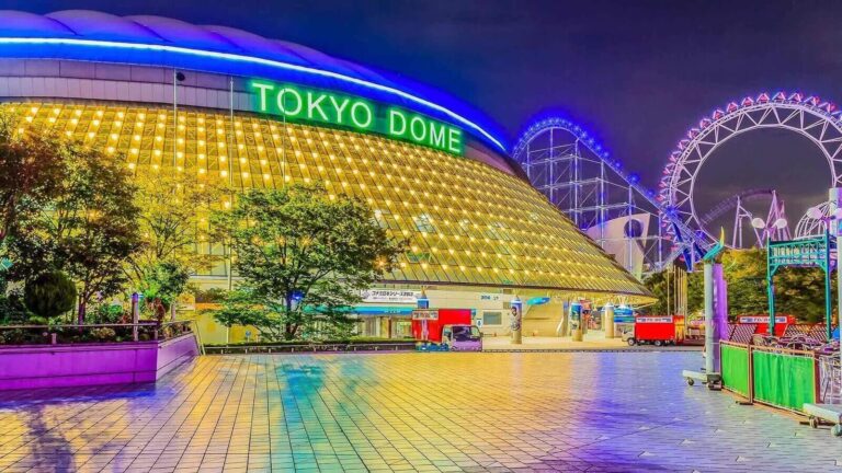 Vibrant Tokyo Dome illuminated at night with a colorful amusement park in the background, showcasing a lively urban atmosphere.