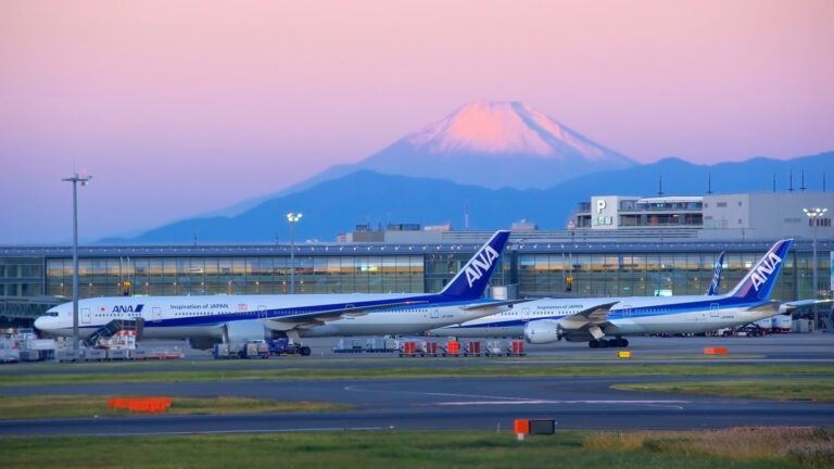 "ANA airplanes at the airport with Mount Fuji in the background during a pastel sunset, symbolizing travel and adventure."