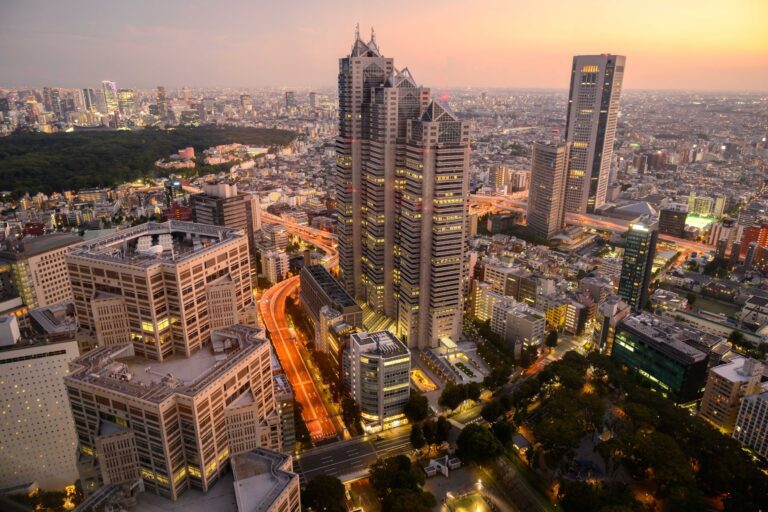 Aerial view of Tokyo's skyline at sunset, showcasing modern architecture and vibrant city life against a colorful sky.