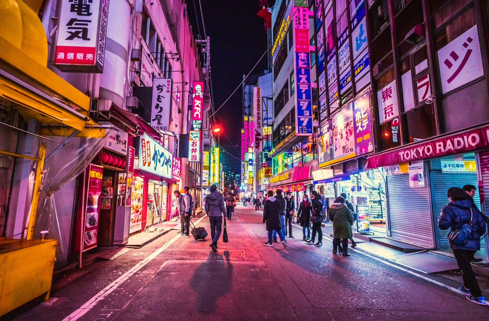 people walking between city building in Akihabara, Tokyo, Japan