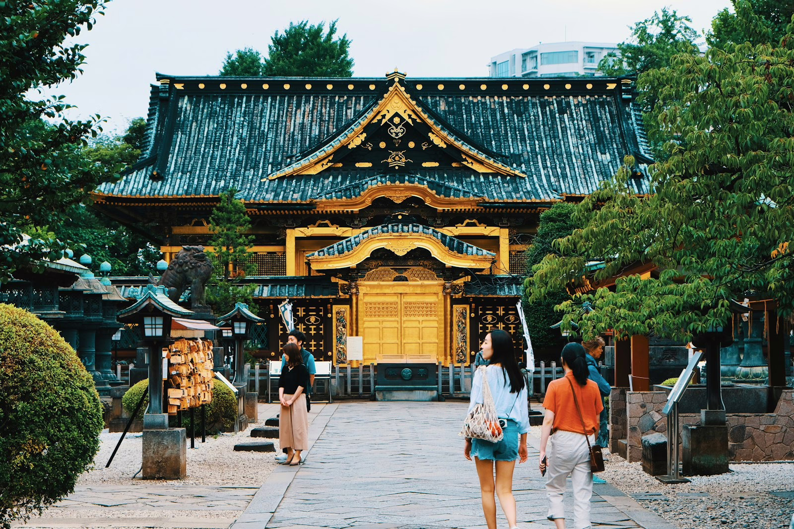 Visitors exploring a serene temple courtyard, surrounded by lush greenery and traditional Japanese architecture.