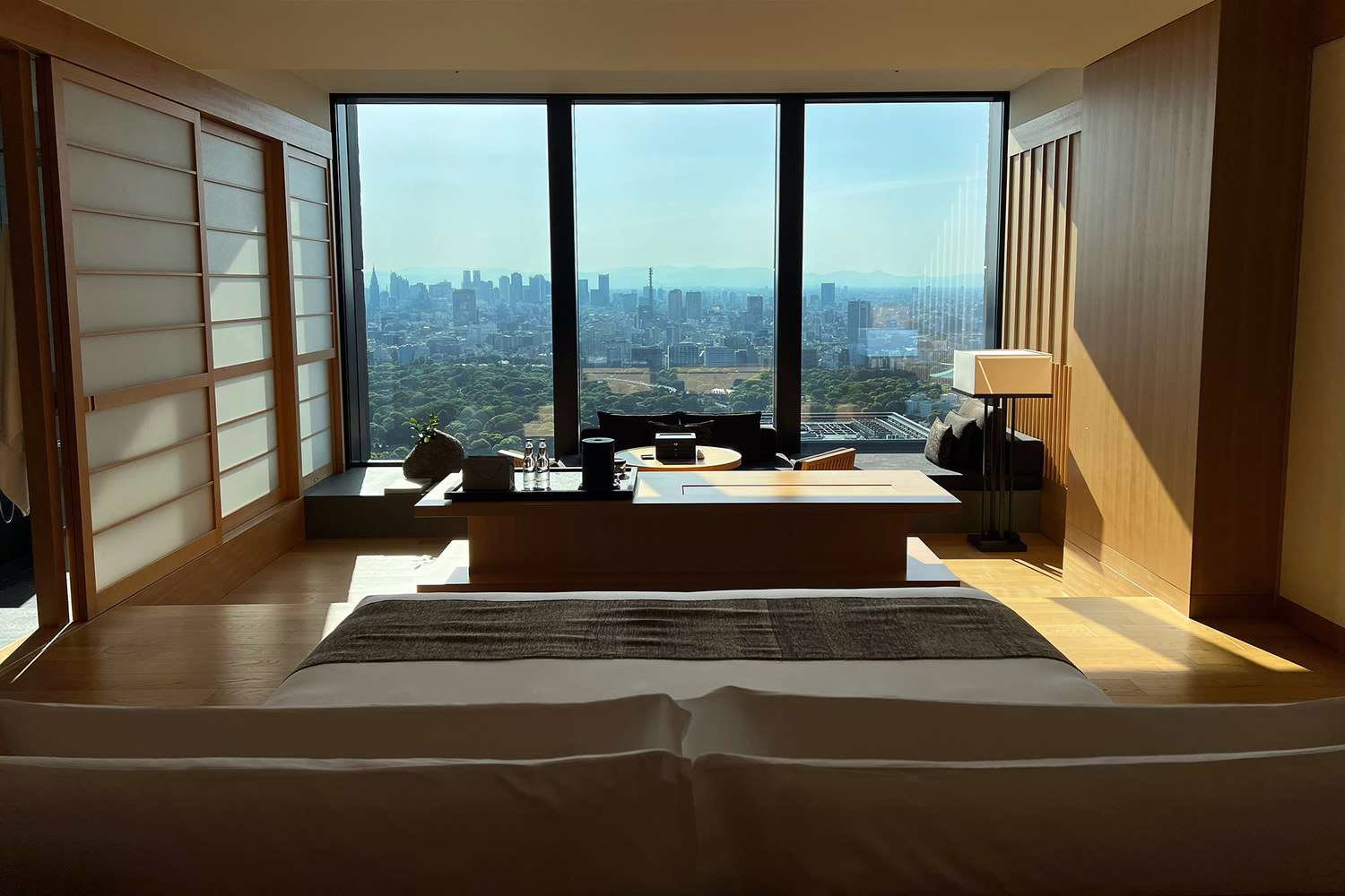 Modern hotel room with elegant wood furnishings, panoramic city views, and a serene ambiance for relaxation.