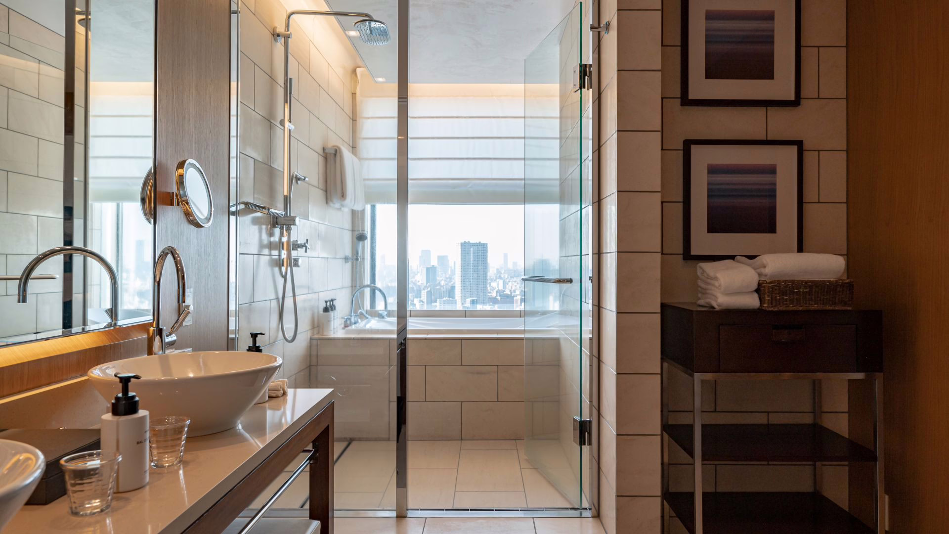 Modern hotel bathroom with elegant fixtures, a soaking tub, and a scenic city skyline view through large glass windows.