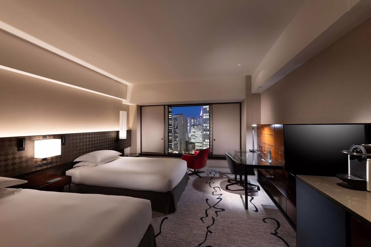 Modern hotel room with a cozy seating area, large windows offering city views, and a sleek workspace for business travelers.