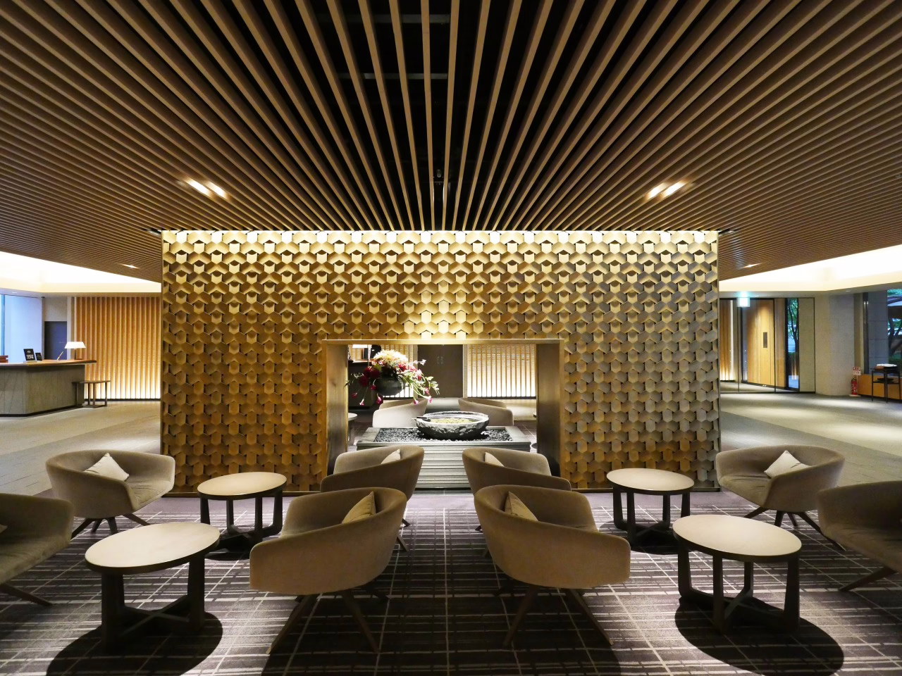 Modern hotel lobby featuring elegant seating around a stylish fire pit, adorned with contemporary decor and warm lighting.