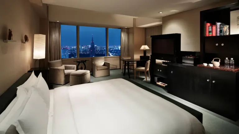 Modern hotel room featuring elegant decor and a stunning city view at night, perfect for a luxurious stay.