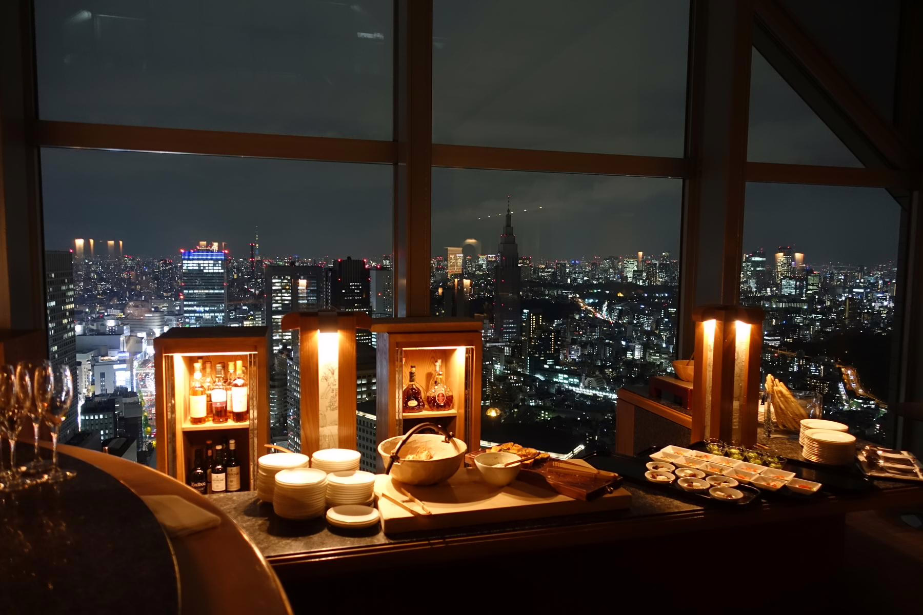 Elegant evening buffet in a high-rise restaurant, showcasing delicious dishes with a stunning city skyline at night.