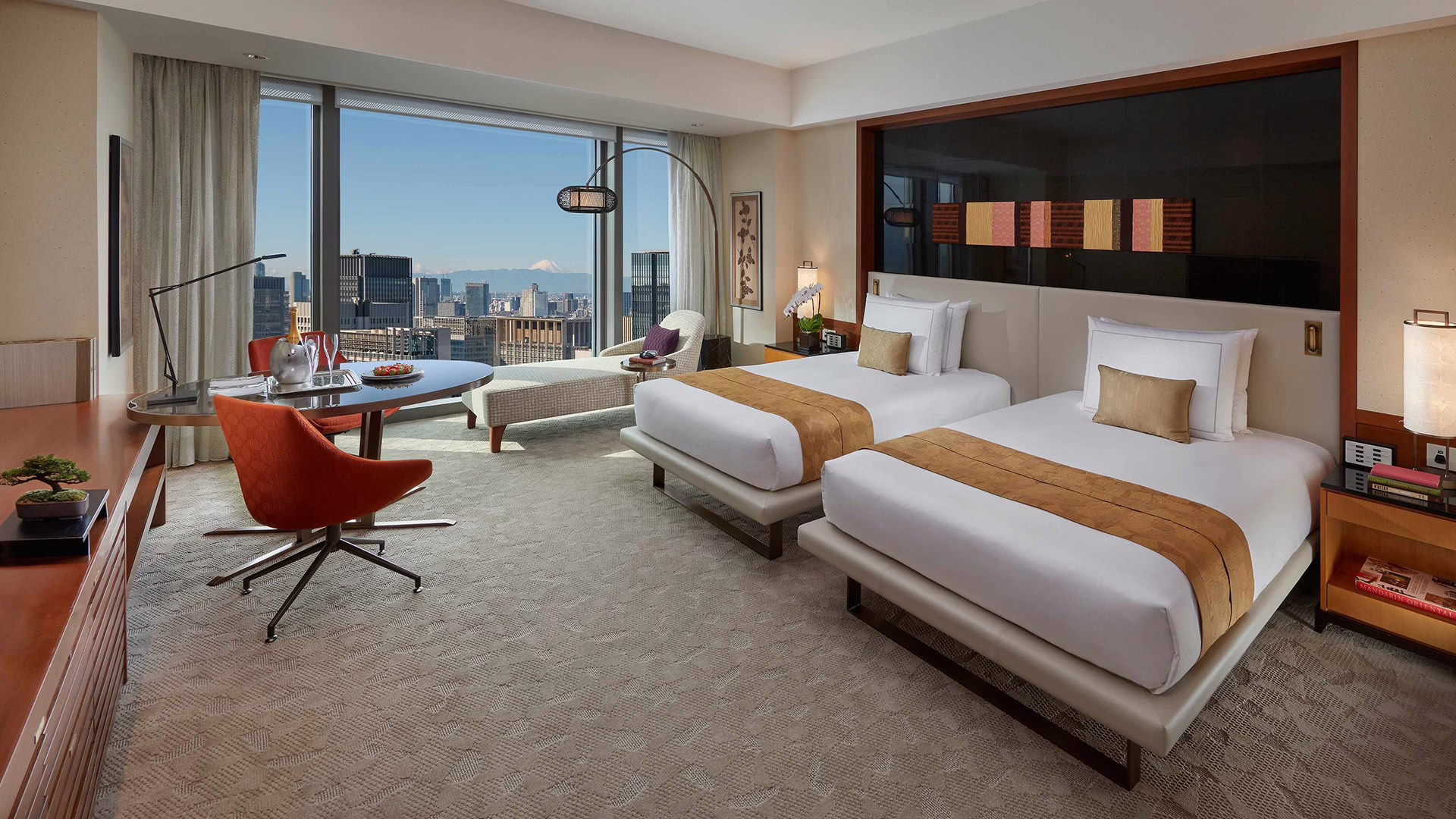 Luxurious hotel room featuring two beds, modern decor, and a stunning city view through large windows.