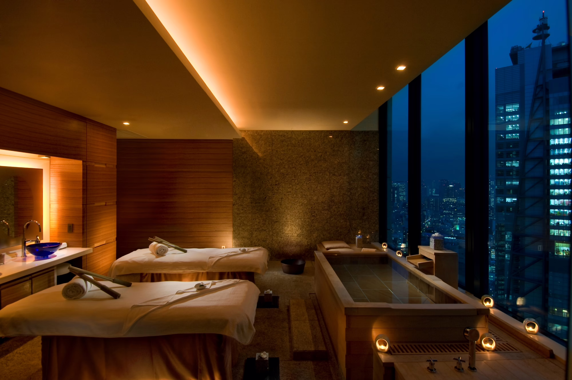 Luxurious spa room with massage tables and a serene city view, ideal for relaxation and rejuvenation after a long day.