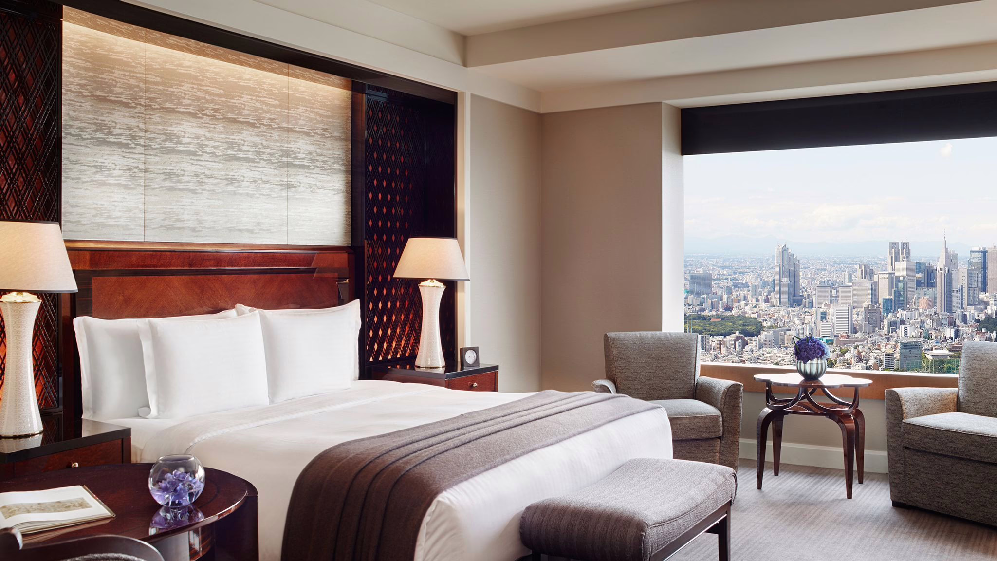 Luxurious hotel room with city skyline views, featuring a plush bed, stylish decor, and inviting seating area for relaxation.