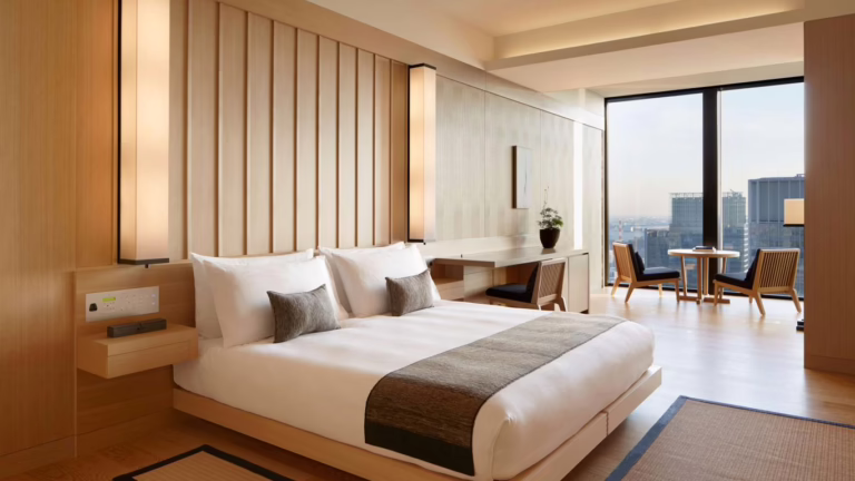 Contemporary hotel room featuring a cozy bed, stylish furniture, and panoramic city views, ideal for a relaxing stay.