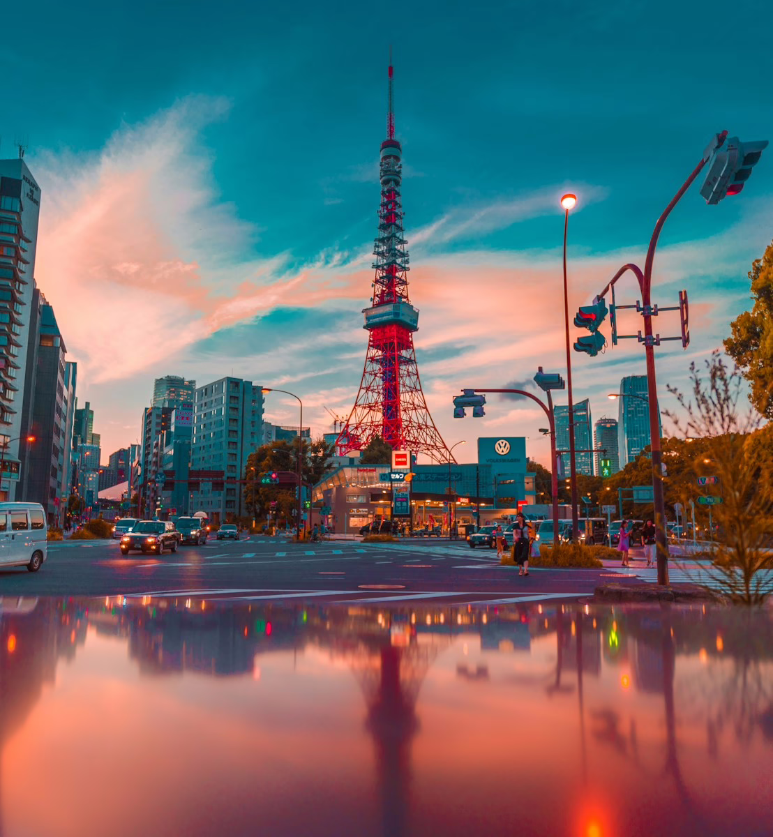 Tokyo Tower illuminated against a vibrant sunset, surrounded by bustling city streets and modern architecture.