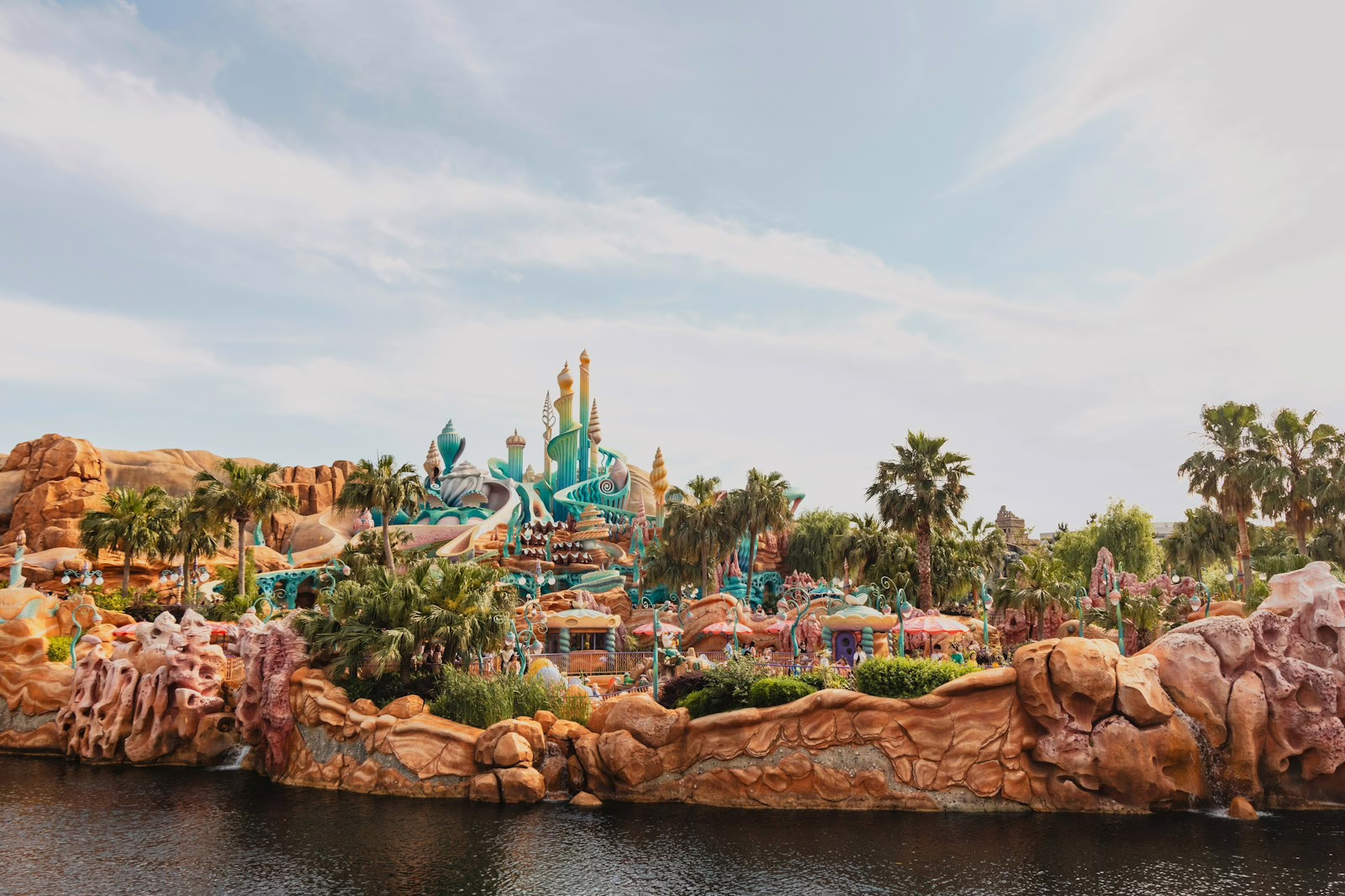 Vibrant underwater-themed amusement park with colorful structures and lush palm trees, reflecting a whimsical seaside adventure.