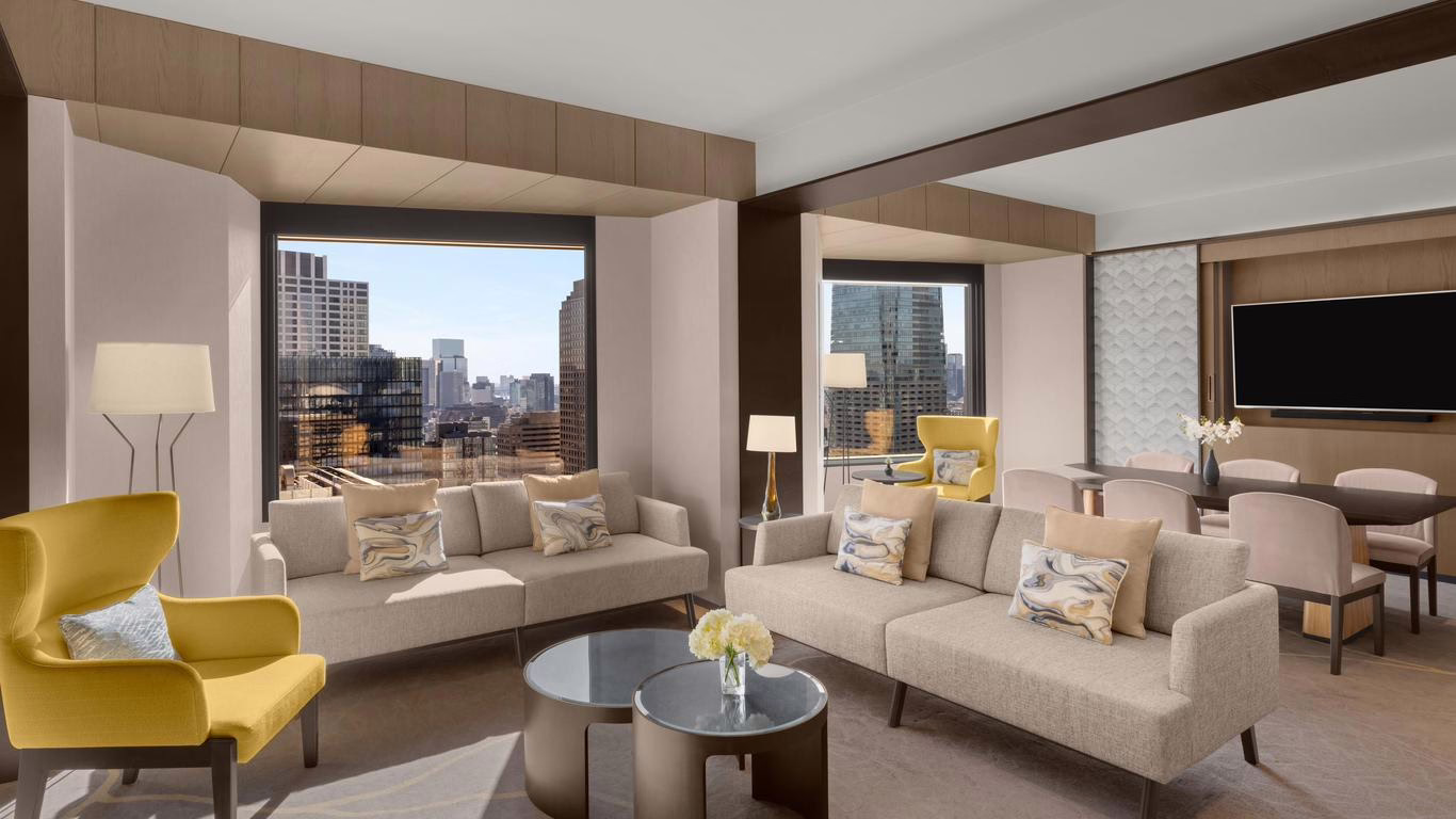 Modern hotel suite showcasing stylish seating, panoramic city views, and elegant decor, perfect for relaxation or business stays.