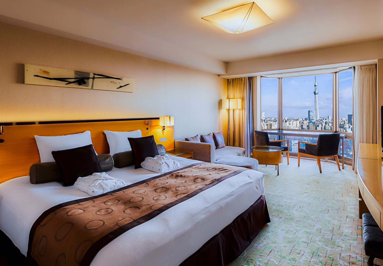 Luxurious hotel room with scenic city views, featuring a cozy bed, sitting area, and modern decor, ideal for relaxation.