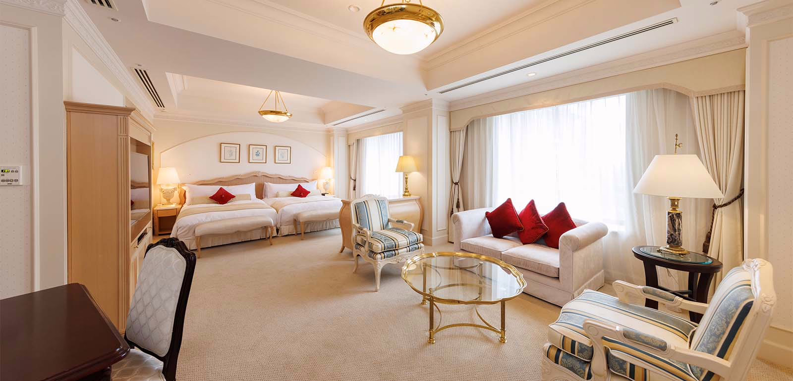 Luxurious hotel room featuring elegant decor, twin beds, and a cozy sitting area with plush furniture and natural light.