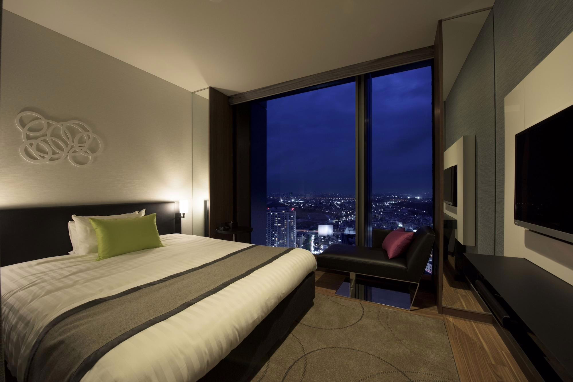 Modern hotel room with a cozy bed, stylish decor, and stunning city views at night, perfect for travelers seeking comfort.