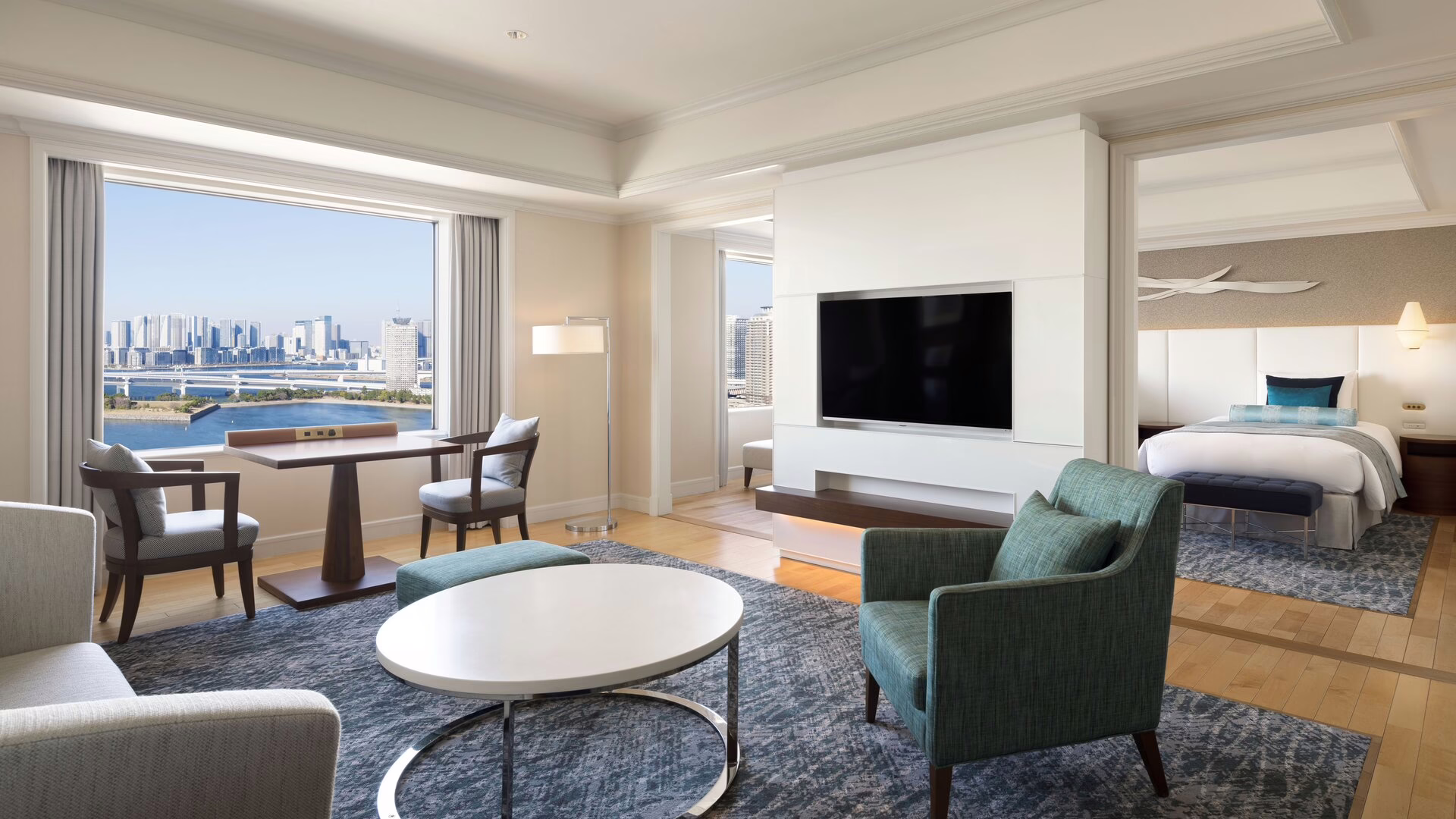 Modern hotel suite with a stunning city view, featuring stylish furnishings and a serene atmosphere for relaxation.