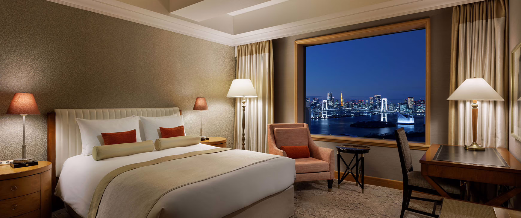 Luxurious hotel room with a stunning city skyline view at night, featuring elegant decor and a cozy atmosphere.