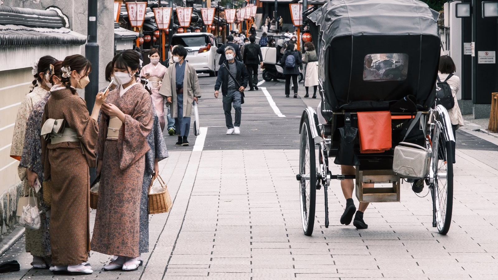 a group of people walking down a sidewalk next to a carriage