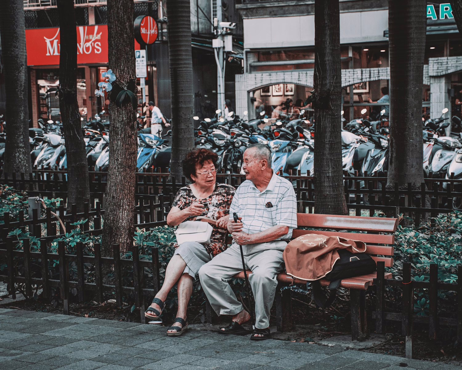 man and woman sitting on brown wooden bench during daytime