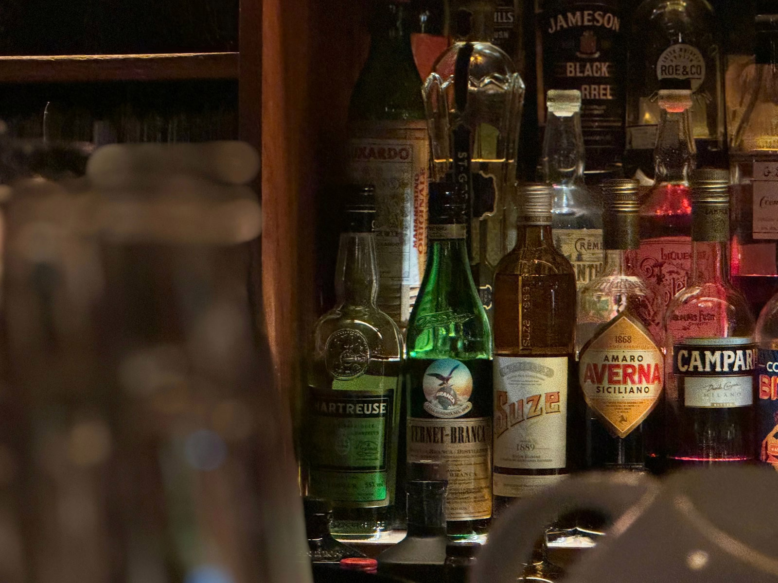 A shelf full of liquor bottles and liquor glasses