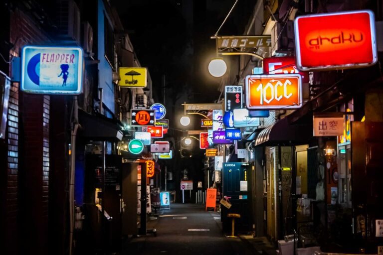 Vibrant nightlife scene in an alley filled with illuminated signs from restaurants and bars, capturing Tokyo's urban charm.