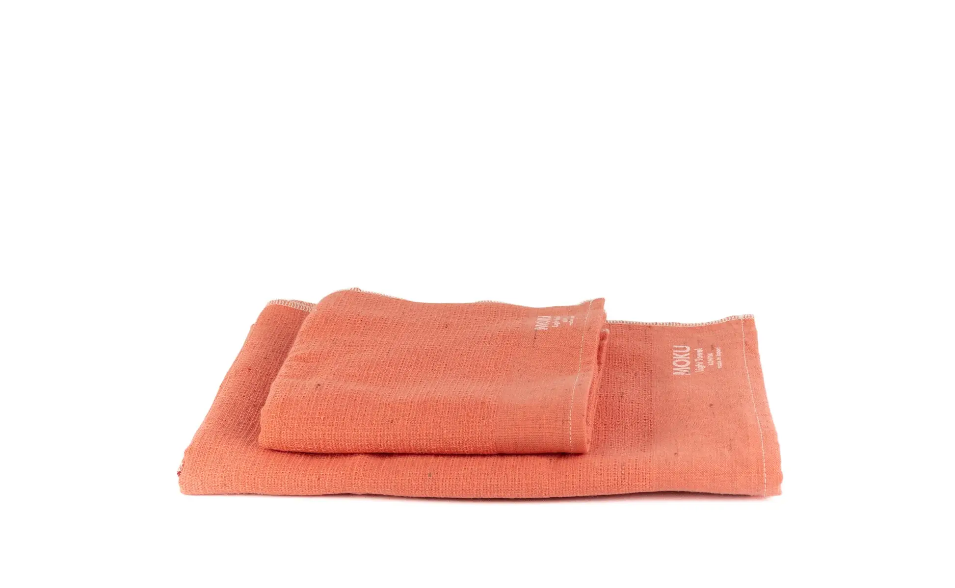 Soft coral kitchen towels neatly stacked, ideal for adding color and functionality to any cooking space.
