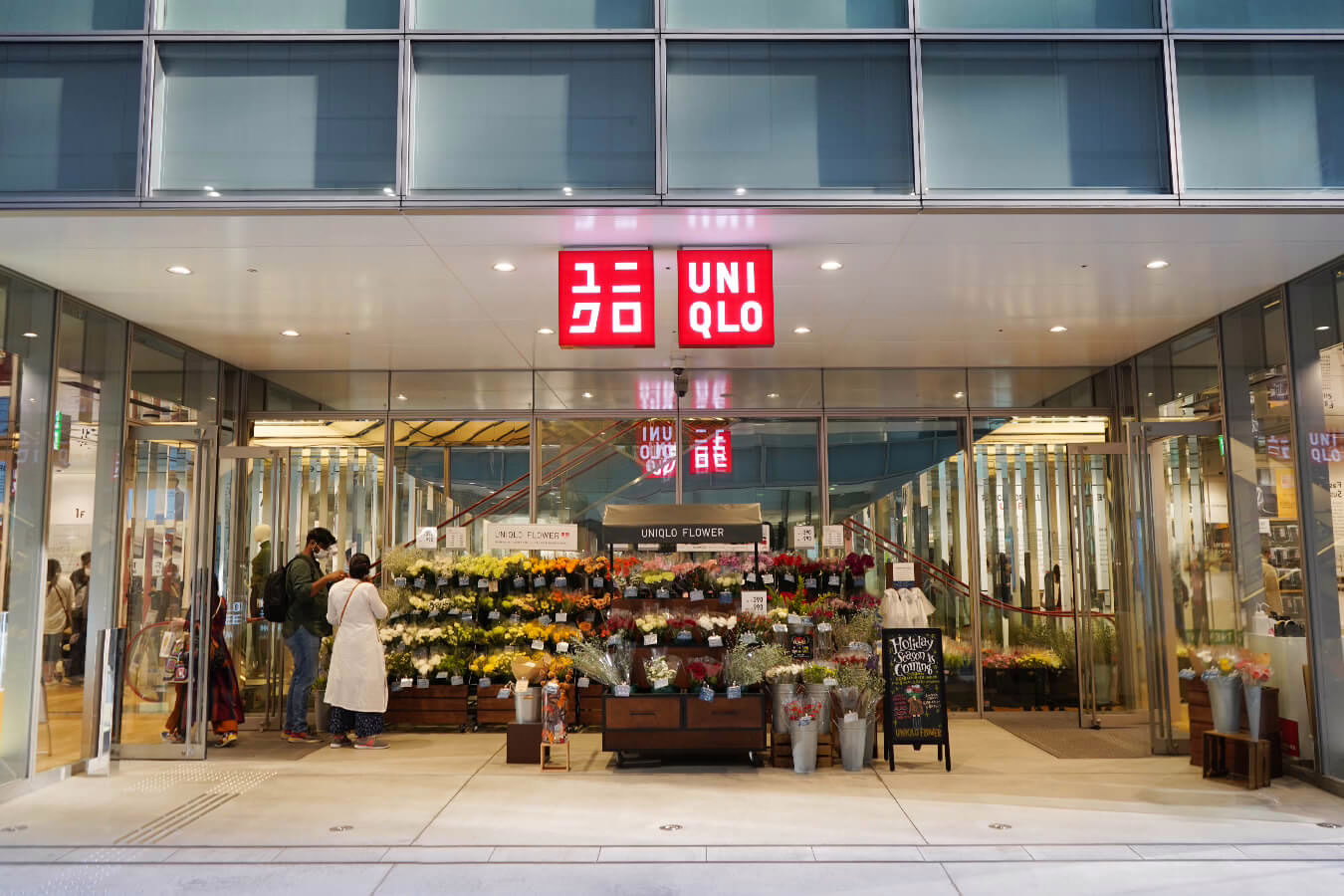 "UNIQLO store entrance featuring a vibrant flower display, inviting customers to explore stylish clothing and floral arrangements."