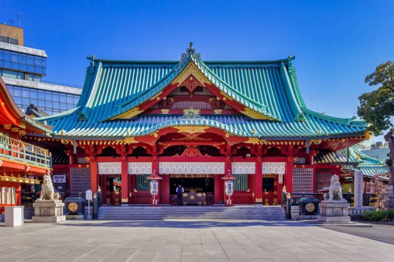 Colorful Japanese shrine with intricate architecture, showcasing vibrant roofs and stone guardian lion statues.