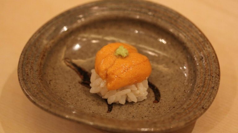 Fresh sea urchin sushi topped with wasabi served on a handcrafted ceramic plate, highlighting exquisite Japanese cuisine.