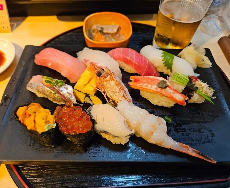 Fresh sushi platter featuring assorted nigiri, sashimi, and delectable rolls, accompanied by a refreshing beer.