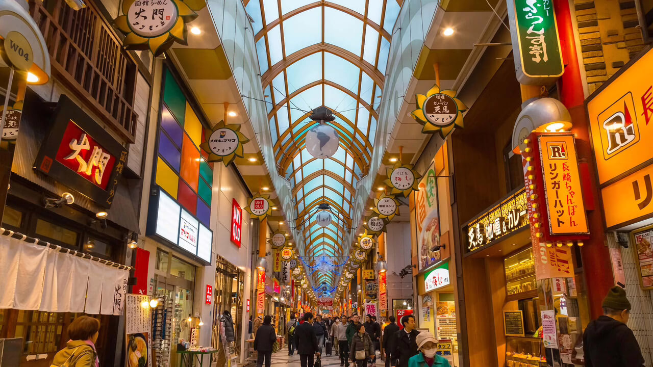 Bustling shopping street showcasing diverse shops, colorful signage, and a lively atmosphere in a modern market.