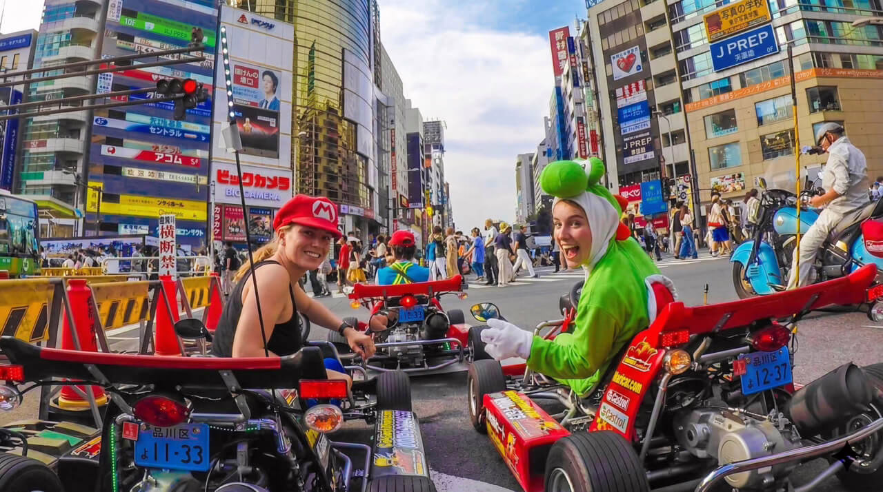 Participants in costumes driving go-karts through a bustling Tokyo street, capturing the excitement of urban adventure.